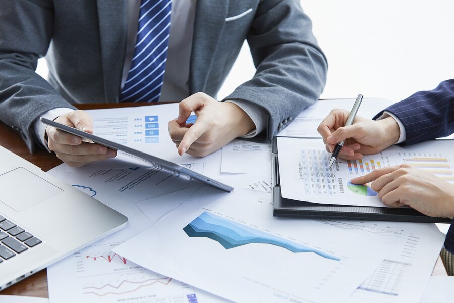 Business professionals analyzing financial reports and graphs on a table, discussing tax resolution strategies for clients.