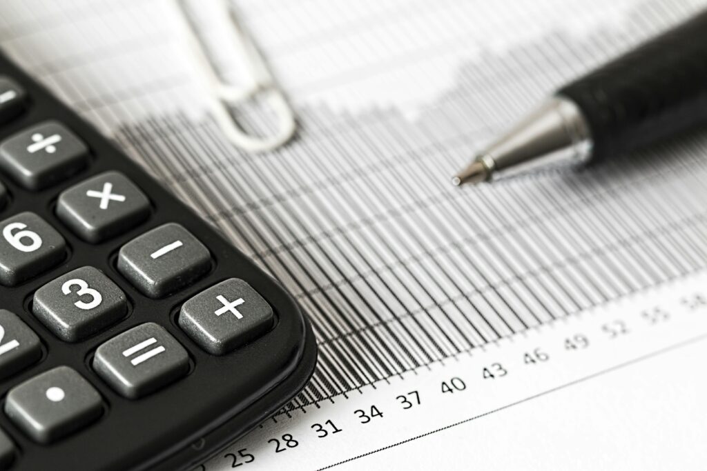 Calculator and pen on financial documents, representing tax calculations and small business financial management for IRS issues.
